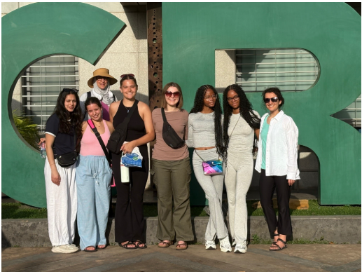 A diverse group smiles for a photo with arms around each other