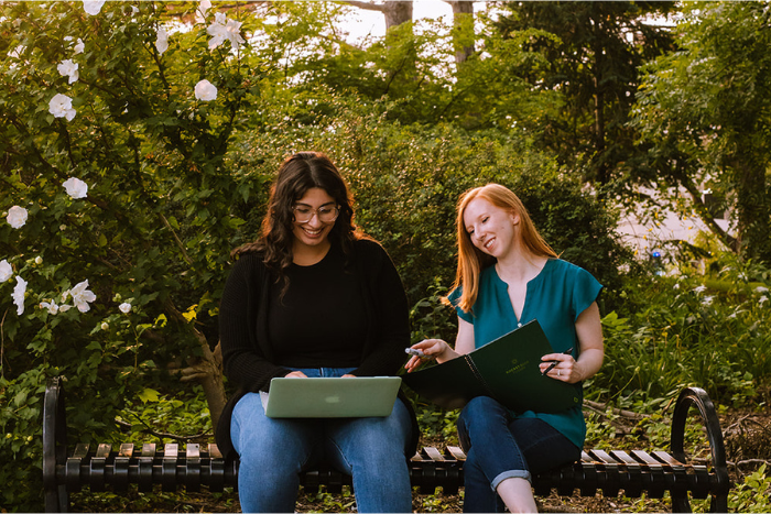 two students sitting on a bench studying