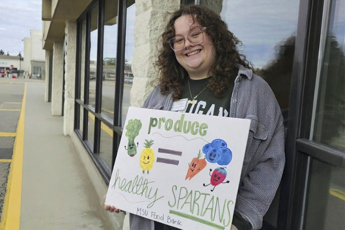 Student holding a healthy Spartans sign outside